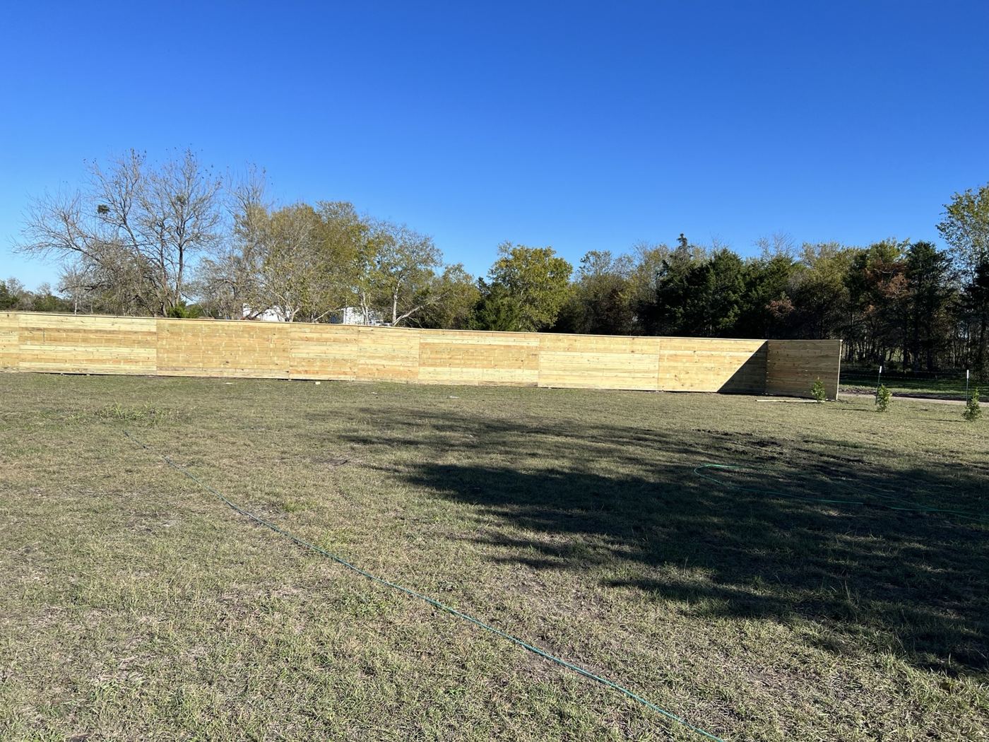 Long wood privacy fence installed across a large open property